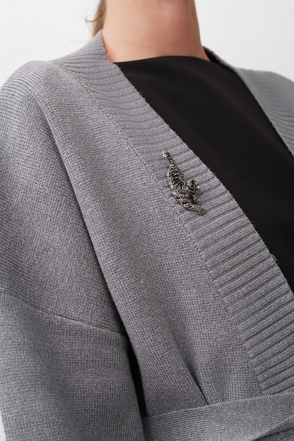 Cardigan with a belt and brooch.