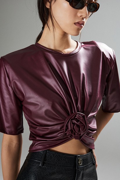 Cropped faux leather blouse with decorative flower