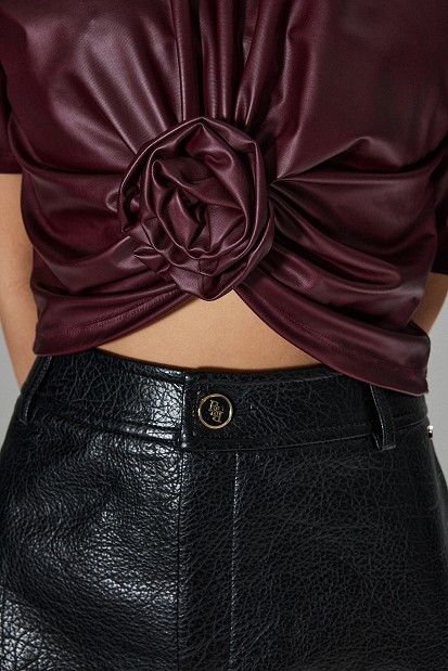Cropped faux leather blouse with decorative flower